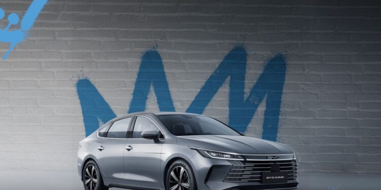 BYD King L sedã híbrido prata estacionado em frente a parede com grafite azul, mostrando design moderno e elegante do veículo chinês