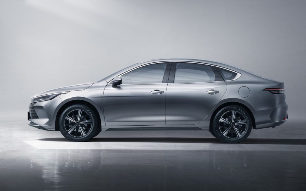 BYD King L híbrido prata visto de perfil lateral em estúdio, destacando design aerodinâmico, rodas esportivas e silhueta elegante do sedã