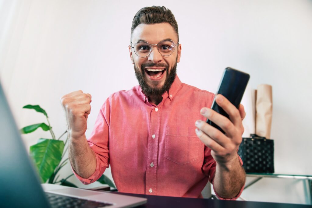 Pessoa comemorando ganhos renda extra smartphone trabalho casa sucesso financeiro