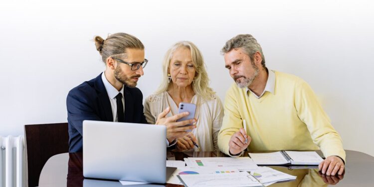 Consultor financeiro mostrando opções de empréstimo SuperSim em celular para casal idoso.