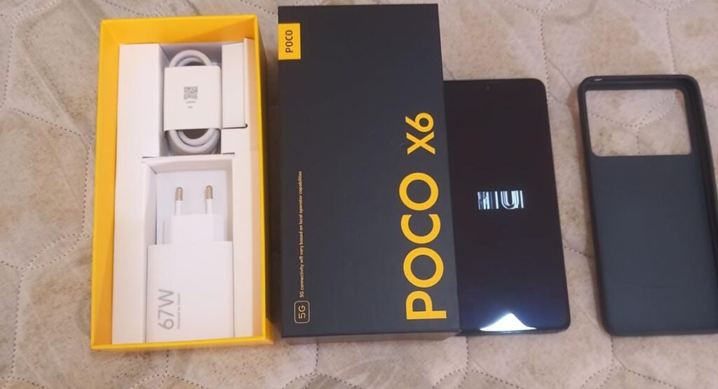 Xiaomi POCO X6 5G unboxing mostrando caixa preta, carregador 67W, cabo USB-C, smartphone ligado e capa protetora