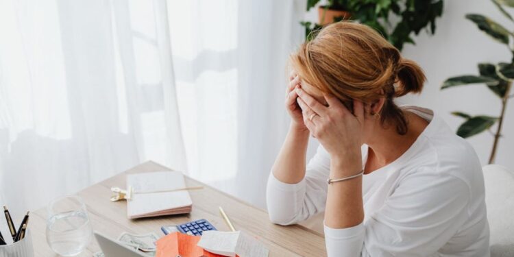 Mulher preocupada com contas e finanças em mesa de escritório.